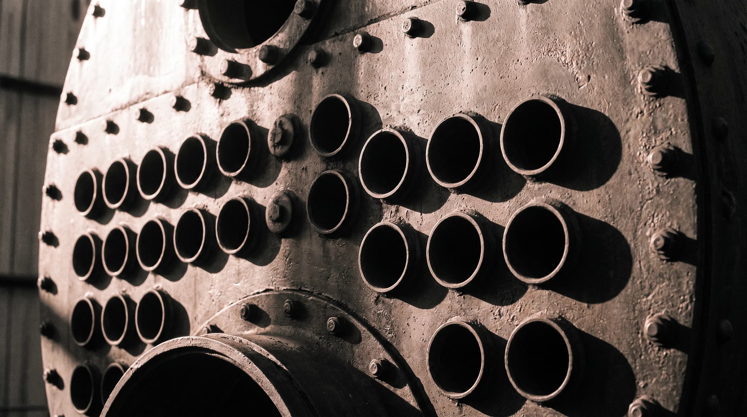 Riveted face of a commercial fire-tube boiler in dramatic side light